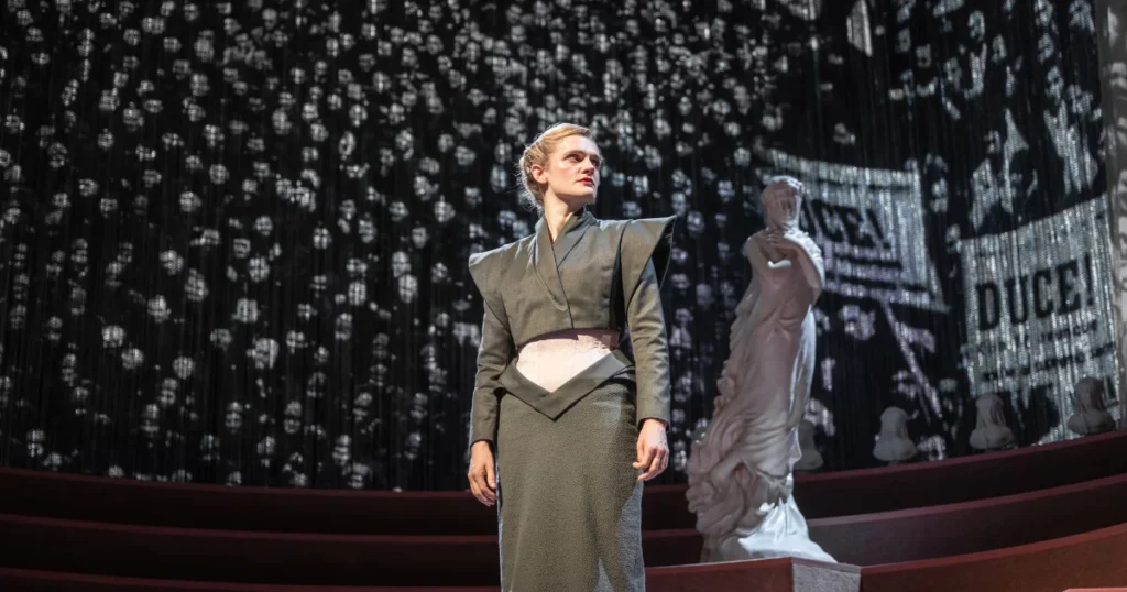 Gayle Rankin as Miss Jean Brodie oi front of faces of a fascist crowd.